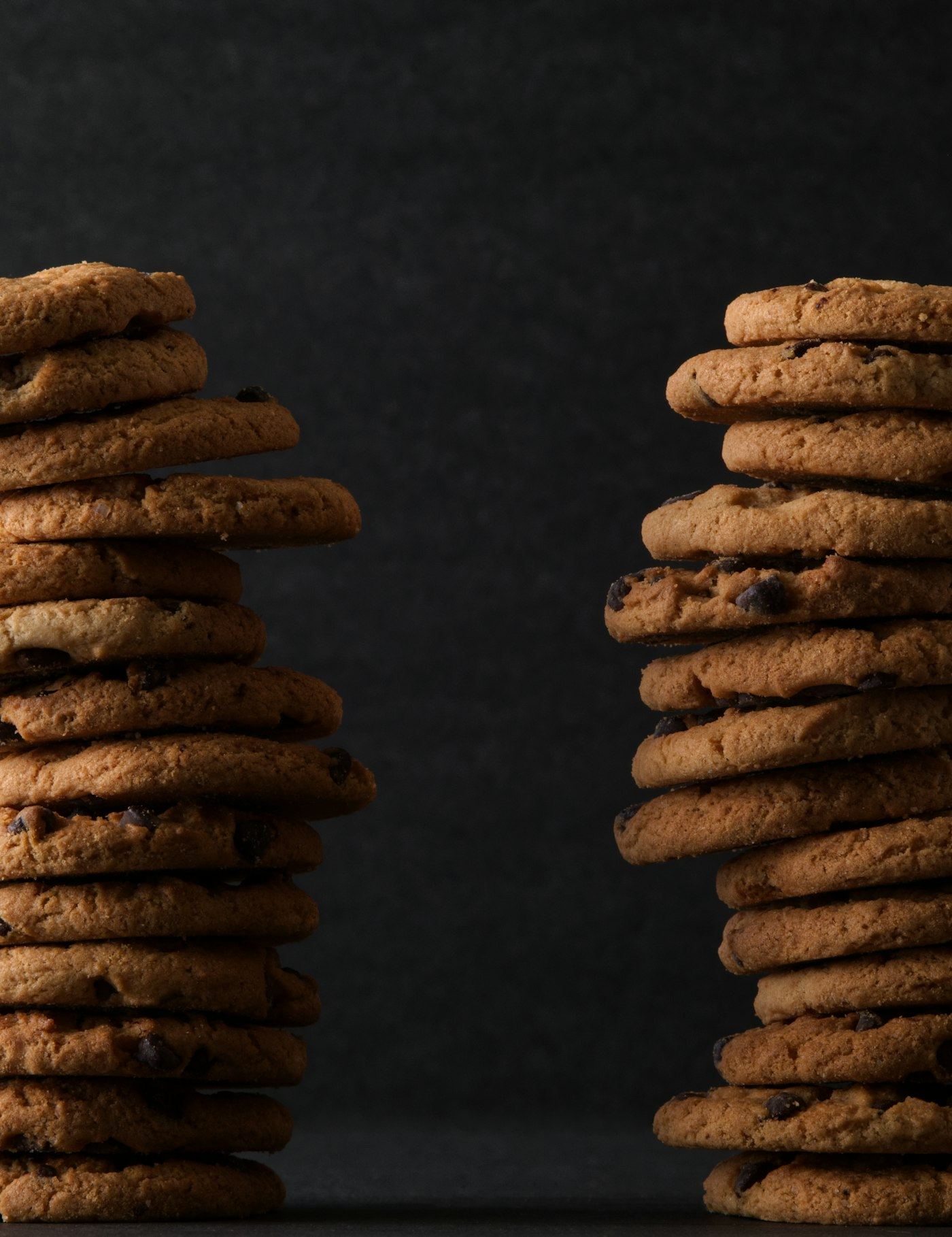 Two tall stacks of golden biscuits against a dark background